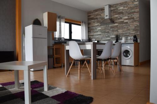 a kitchen with a table and white chairs in a room at Casa do Dragoeiro in Angra do Heroísmo
