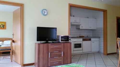 a kitchen with a flat screen tv on a wooden cabinet at Ferienhof Stobbe in Grube