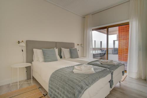 1 Schlafzimmer mit 2 Betten und einem großen Fenster in der Unterkunft Ocean Blue Apartment & Studio in Monte Estoril