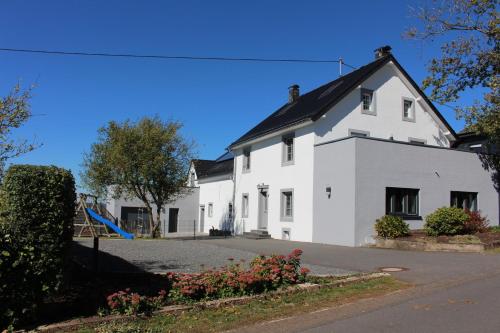 a white house with a playground in front of it at Eifel Dream Schneifelhaus in Kobscheid