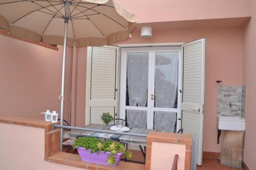 um pátio com uma mesa e um guarda-chuva em Apartments Di Salvo em Furnari
