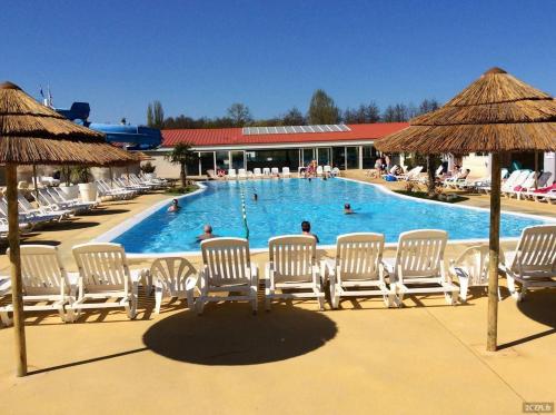 une piscine avec des chaises et des gens dans l'eau dans l'établissement Mobilhome 6 places Les Charmettes 81, aux Mathes
