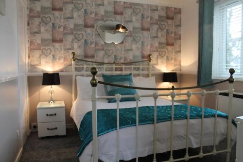 a bedroom with a bed and two lamps and a wall at Darcey's Apartment in Bowness-on-Windermere