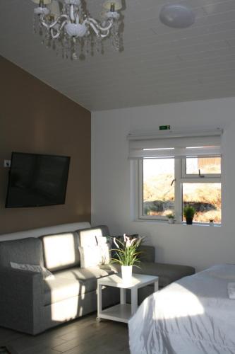 a bedroom with a bed and a couch and a chandelier at Country Dream - Langholt 2 in Selfoss