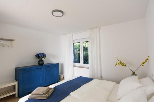 a white bedroom with a blue cabinet and a bed at Modern & Comfy Sea View House NG in Portorož