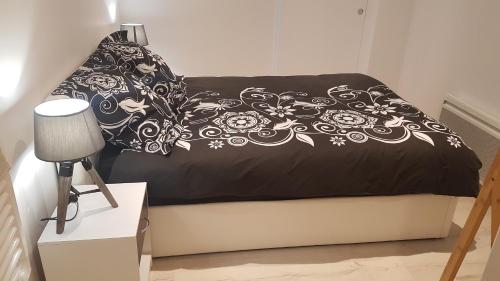 un letto con una coperta bianca e nera e una lampada di Appartement T2 proche gare et centre Bourgoin a Bourgoin