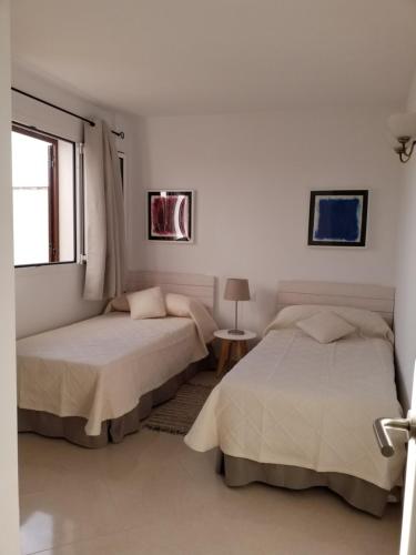 two beds in a white room with a window at SEA ONE. in Port de Pollensa
