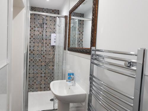 a white bathroom with a sink and a shower at The Snug at Plover Cottage Lindley in Huddersfield