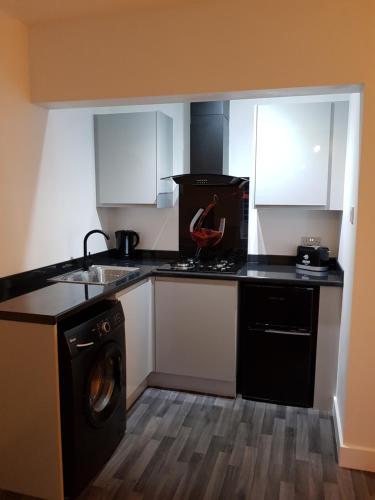 a small kitchen with a washer and a stove at The Snug at Plover Cottage Lindley in Huddersfield