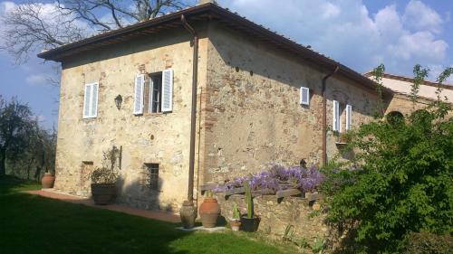 an old stone building with flowers in front of it at Podere San Quirico in Castelnuovo Berardenga