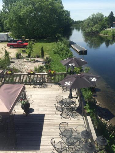 a deck with tables and umbrellas next to a river at Dominion Hotel in Minden
