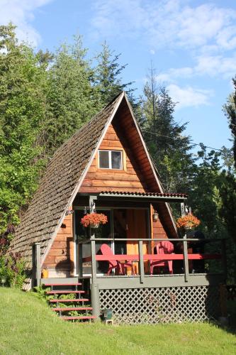 a cabin with a thatched roof and red chairs at Sunny Bluffs Chalets in Kaslo