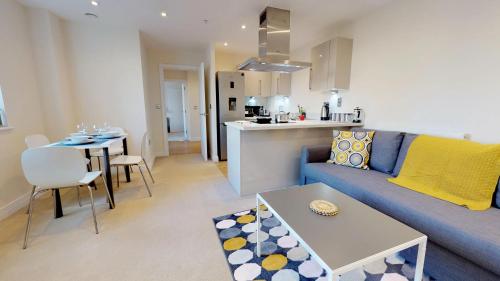a living room with a blue couch and a kitchen at NIKSA Serviced Accommodation - Welwyn Garden City Business Park in Welwyn Garden City