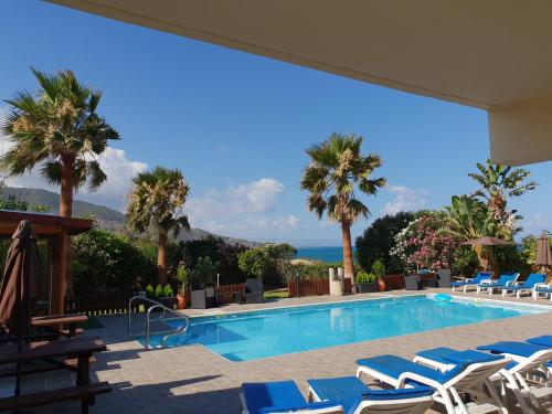 a swimming pool with lounge chairs and palm trees at Kanalli Apartments in Pomos