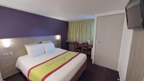 a hotel room with a large bed and a table at Kyriad Chantilly Sud - Luzarches in Chaumontel