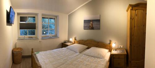 a bedroom with a white bed and two windows at Haus Hugo in Zingst