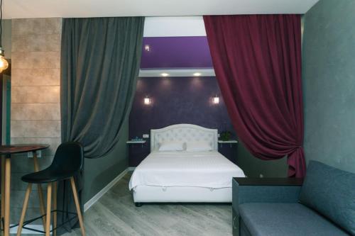 Schlafzimmer mit einem weißen Bett und roten Vorhängen in der Unterkunft Дизайнерская Студио 10 мин метро Позняки in Kiew