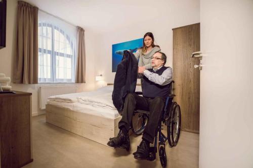 a man in a wheelchair in a bedroom with a woman at Kings Residence in Prague