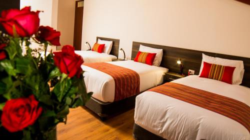 two beds in a hotel room with red roses at Hotel San Pedro Plaza in Cusco