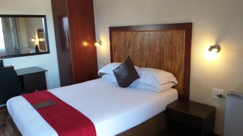 1 dormitorio con 1 cama blanca grande con manta roja en Road Stay en Maseru