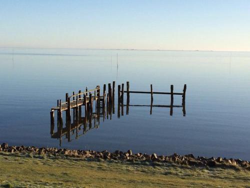 a reflection of a dock in a body of water at Inselhotel Kapitän Tadsen / Amrum in Nebel