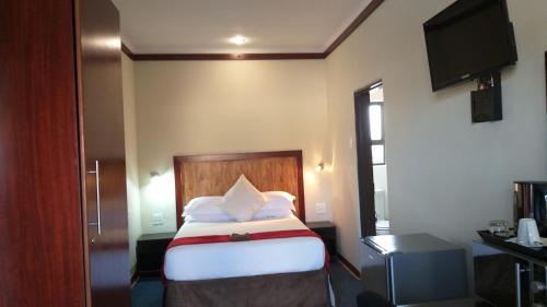 a hotel room with a bed and a flat screen tv at Road Stay in Maseru