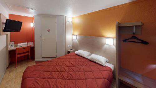 a hotel room with a red bed and a desk at Premiere Classe Chantilly Sud Luzarches in Chaumontel