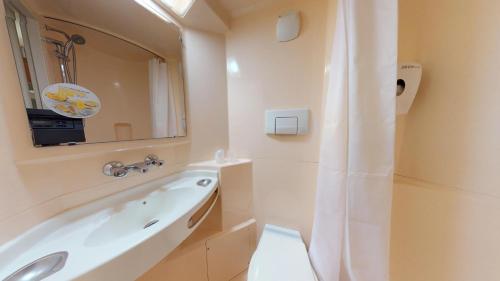 a bathroom with a tub and a sink and a mirror at Premiere Classe Chantilly Sud Luzarches in Chaumontel