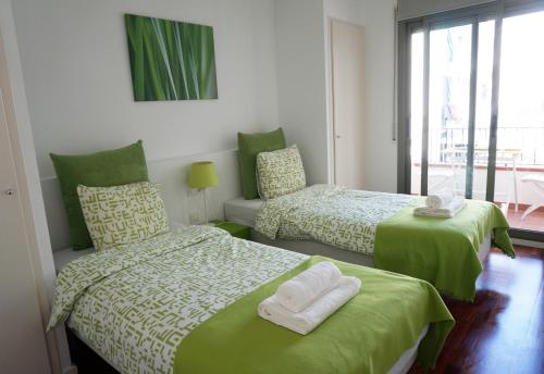 ein Schlafzimmer mit zwei Betten mit grüner Bettwäsche und einem Fenster in der Unterkunft Happy Holiday Beach Home in Sitges