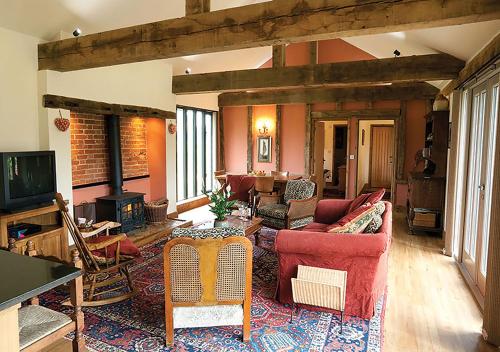 a living room with a couch and a tv at Lackford Lakes Barns in Flempton