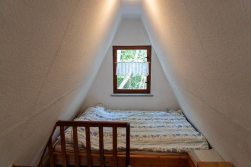 a small bed in a room with a window at Naturcamping Perlin Ferienhaus in Perlin