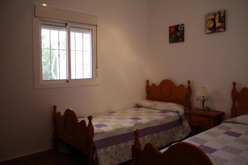 1 dormitorio con 2 camas y ventana en Villa Ana en Zahora