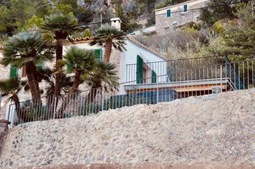 a white house with palm trees and a fence at C'an Co Banyalbufar in Banyalbufar