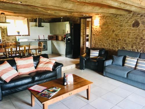 a living room with couches and a table and a kitchen at Forét Enchantée De Bourgogne in La Celle-En-Morvan