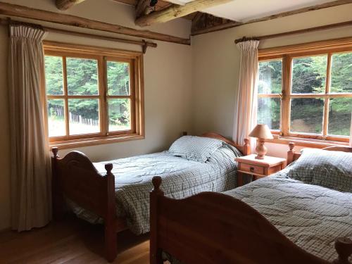 a bedroom with two beds and two windows at Casa Campo Carretera Austral in Puerto Cisnes