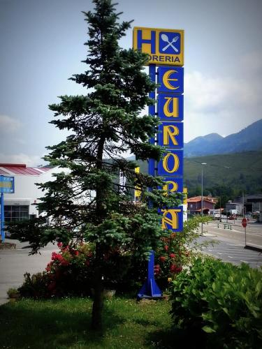 a tree in front of a sign in a parking lot at Hostal Europa in San Roque del Acebal