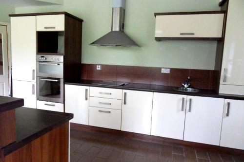 a kitchen with white cabinets and black counter tops at Ethan House in Killarney