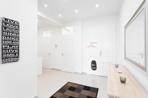 Jest to biały pokój z drewnianym stołem i dywanem. w obiekcie Bright Red Heart Apartment in Leopoldstadt w Wiedniu