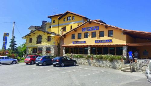 a large yellow building with cars parked in a parking lot at Hostal Europa in San Roque del Acebal