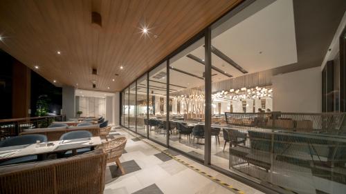 a restaurant with tables and chairs and windows at The Nature Phuket - SHA Extra Plus in Patong Beach