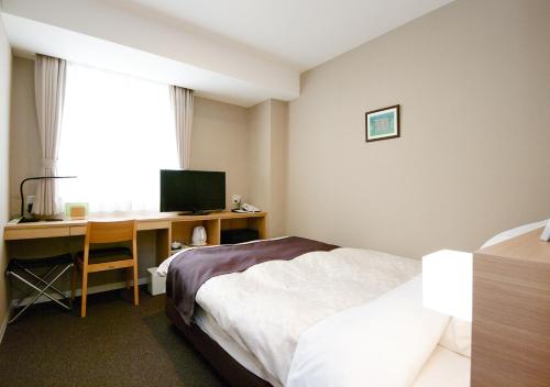 a hotel room with a bed and a desk with a computer at Shibetsu Grand Hotel in Shibetsu City