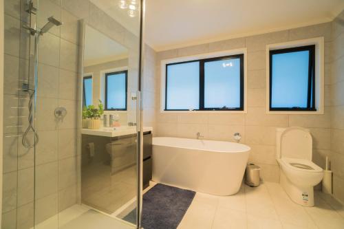 a bathroom with a tub and a shower and a toilet at Amazing Sea Views Luxury Guest House in Hobart