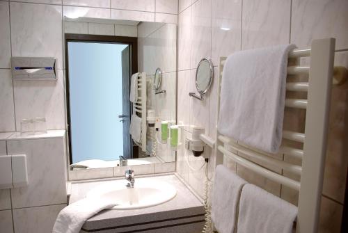 a bathroom with a sink and a mirror and towels at Parkhotel "Am Schänzchen" in Andernach