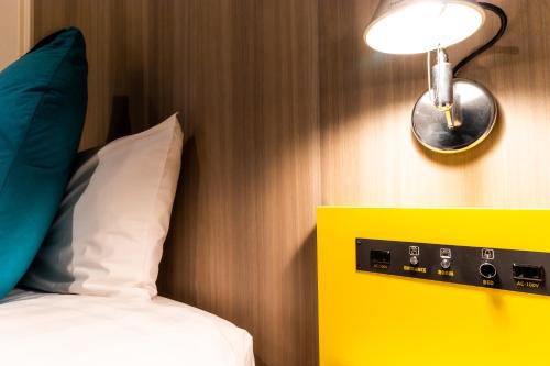 a room with a bed with a light and a pillow at Grand Park Hotel The Luxueux Minami Kashiwa in Kashiwa