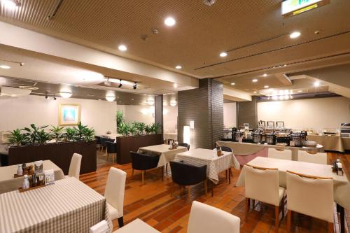 a restaurant with white tables and chairs in a room at Hachinohe Grand Hotel in Hachinohe