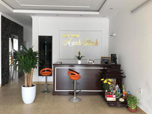 - un salon avec une télévision et deux chaises orange dans l'établissement Nhà nghỉ Mạnh Bình, à Hai Phong