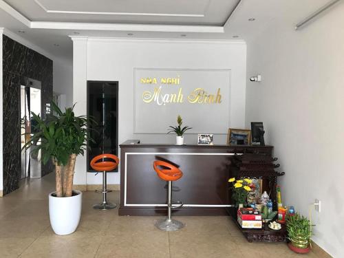 sala de estar con TV y 2 sillas de color naranja en Nhà nghỉ Mạnh Bình, en Hai Phong