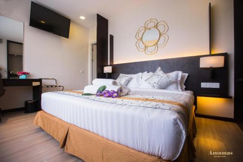 a bedroom with a large bed with white sheets at Amamas Boutique Hotel Kuching in Kuching