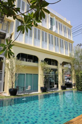 a hotel with a swimming pool in front of a building at Latima Boutique Hostel in Kanchanaburi City