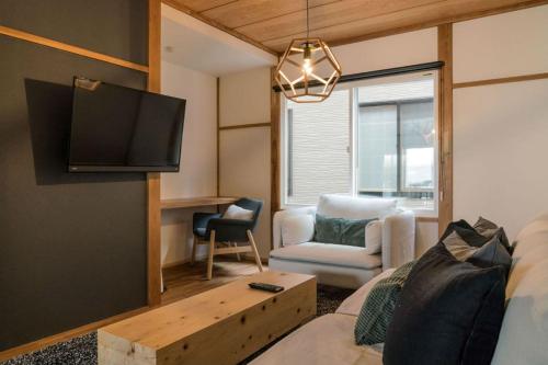 a living room with a couch and a tv at Nozawa Gondola Apartments in Nozawa Onsen